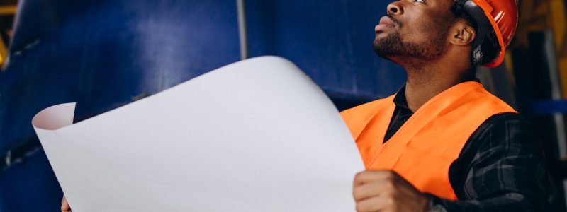 African american worker standing in uniform wearing a safety hat in a factory