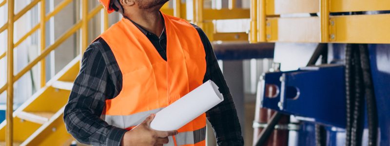 African american worker standing in uniform wearing a safety hat in a factory